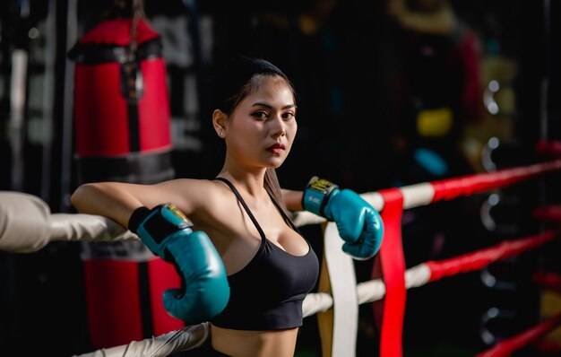 Close up portrait young pretty woman in boxing glove standing on canvas after training with tired, workout in fitness gym,    