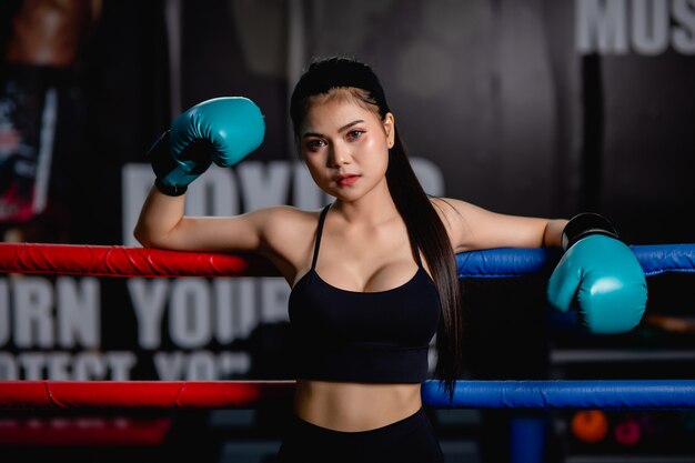 Close up portrait young pretty woman in boxing glove standing on canvas after training with tired, workout in fitness gym,    