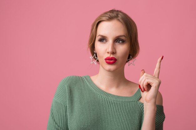 Close up portrait of young pretty woman isolated on pink background, thinking, having idea, holding finger up, elegant style, red lips, spring fashion trend, funny face expression