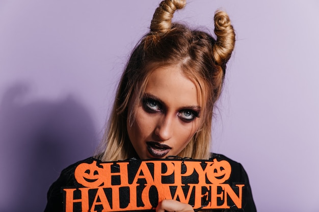 Free photo close-up portrait of young witch with blue eyes. indoor photo of magnificent vampire girl celebrating halloween.