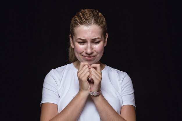 Close up portrait of young woman isolated on black  space. Photoshot of real emotions of female model. Crying, sad, dreary and hopeless