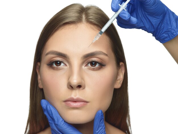 Close-up portrait of young woman isolated on white studio wall in filling surgery procedure