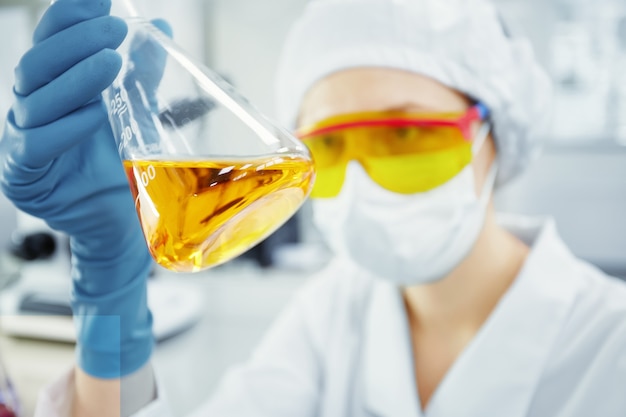 Free photo close up portrait of young woman’s hands holding test tube with yellow liquid