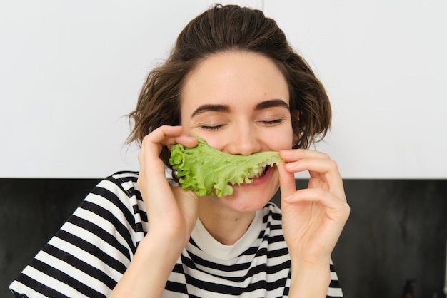 Close up portrait of young woman vegetarian girl likes eating vegetables posing with lettuce leaf