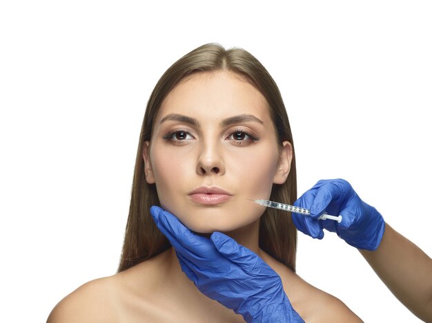 Close-up portrait of young woman on white studio wall. Filling surgery procedure. Lip augmentation.