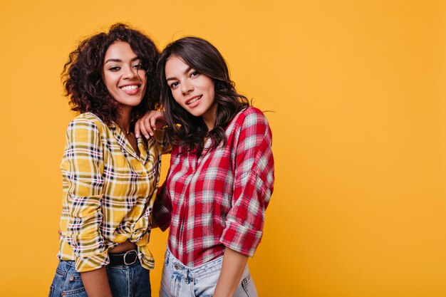 Close-up portrait of young women in checkered shirts. Brown-eyed girls smile cute.
