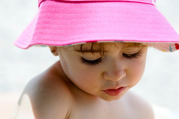 Close-up potrait of adorable little girl outdoors wearing sun hat.