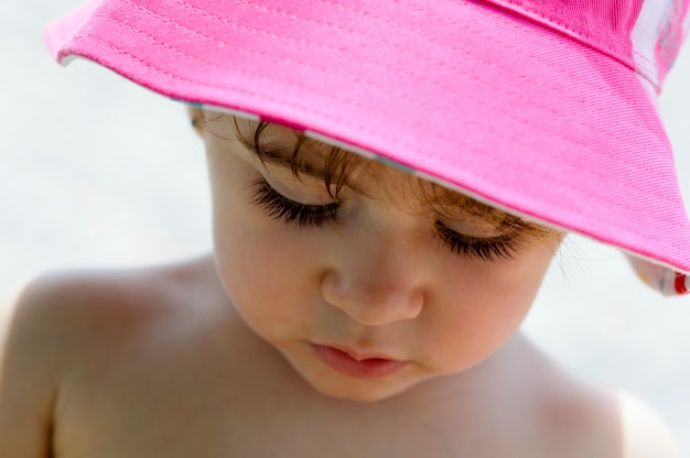 Close-up potrait of adorable little girl outdoors wearing sun hat.