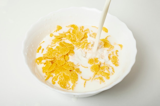 Close up pouring milk in a bowl  with cornflakes