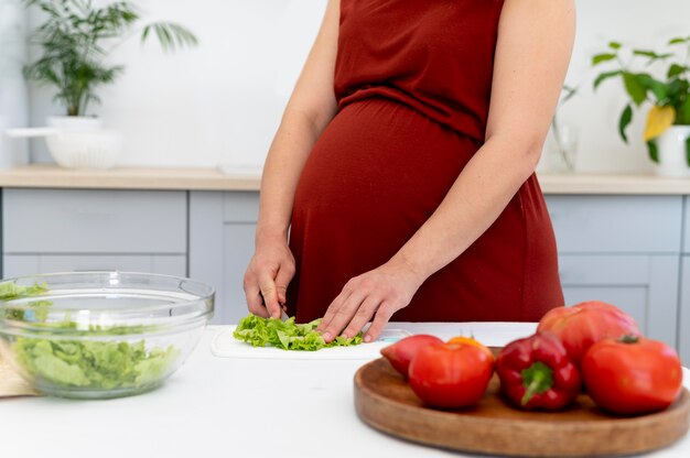 Close up pregnant woman cutting lettuce