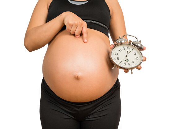 알람 시계를 들고 임신 한 여자의 근접 촬영, 아기를 기대
