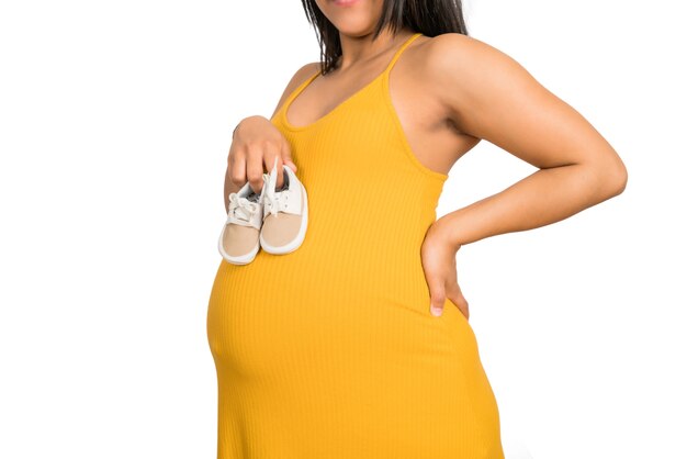 Close-up of pregnant woman holding baby shoes on belly