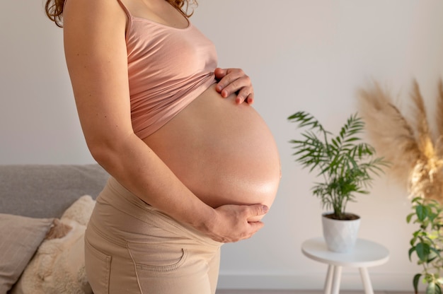 Крупным планом беременная женщина, держащая живот