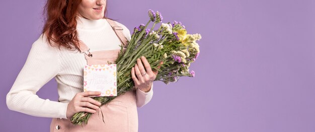 Close-up pregnant woman holding flowers bouquet