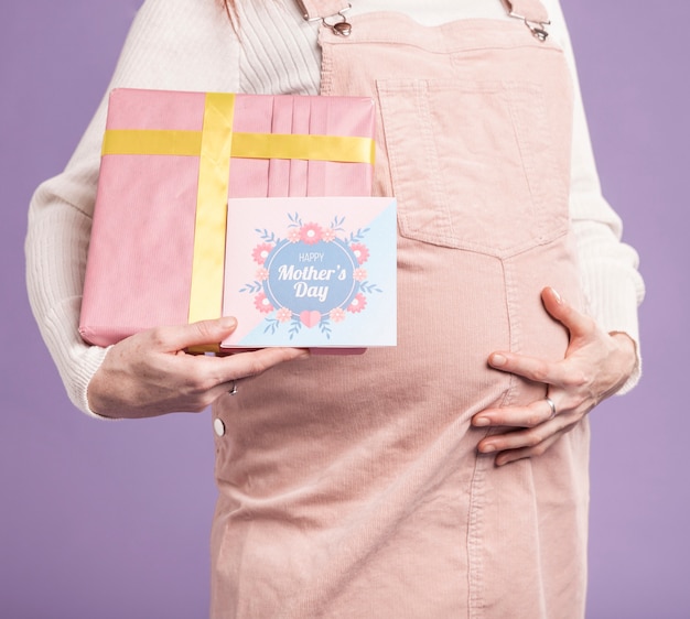Close-up pregnant woman holding gift and greeting card