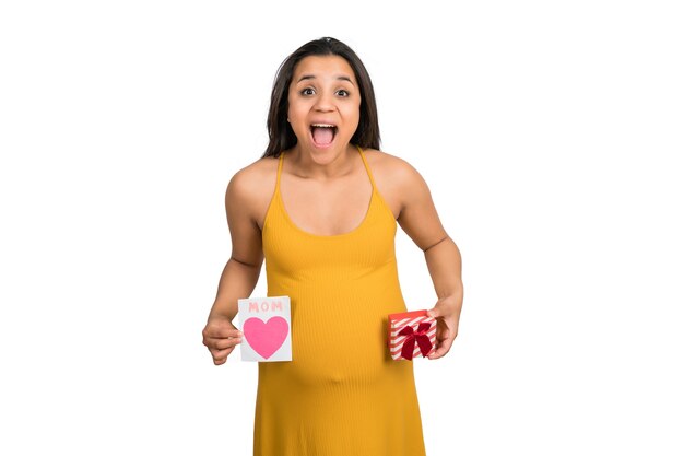 Close-up of pregnant woman holding greeting card and gift box