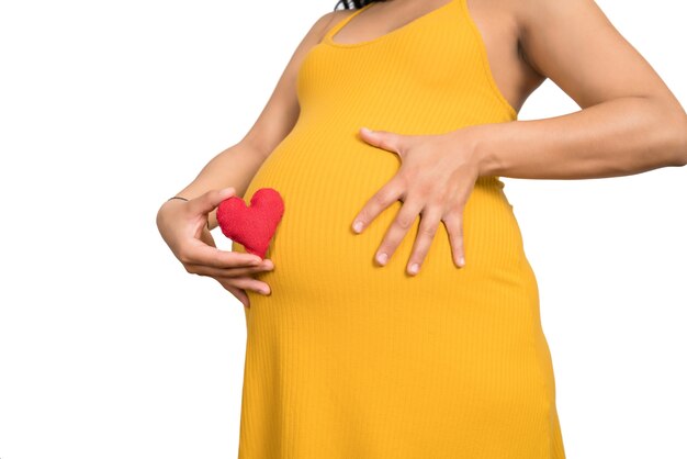 Close-up of pregnant woman holding heart sign on belly