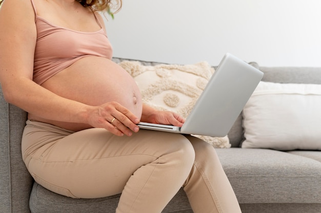 Крупным планом беременная женщина, держащая ноутбук