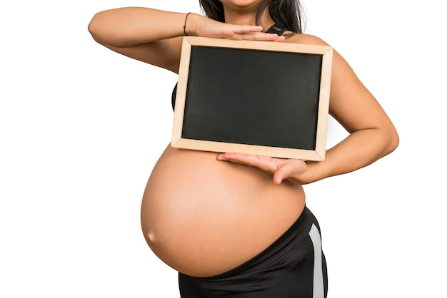 Close-up of pregnant woman holding and showing something on chalkboard