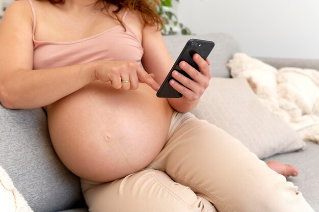 Крупным планом беременная женщина, держащая смартфон