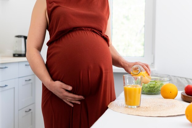 Крупным планом беременная женщина наливает сок