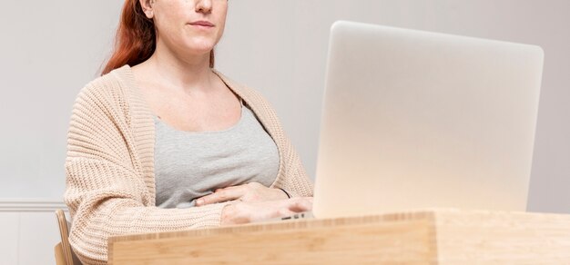 Close-up pregnant woman using laptop