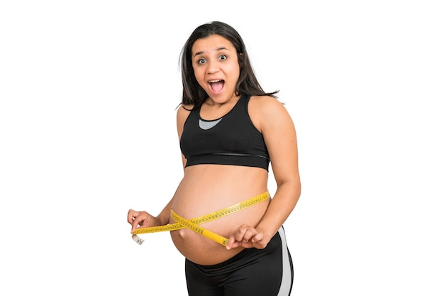 Close-up of pregnant woman using measuring tape to check baby development
