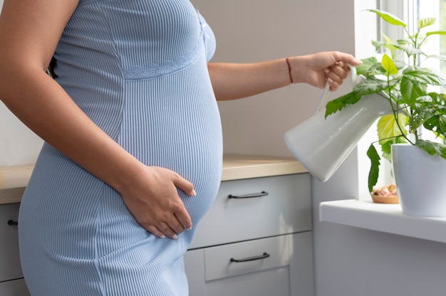 Close up pregnant woman watering plants