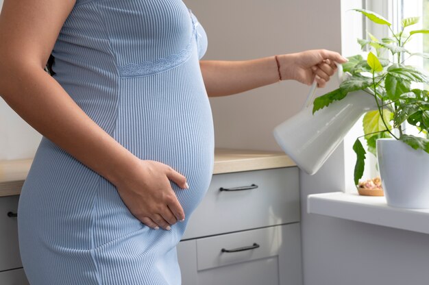 Крупным планом беременная женщина поливает растения