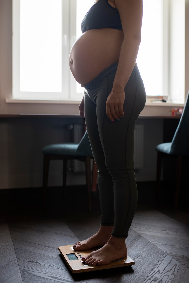 Close up pregnant woman weighing herself