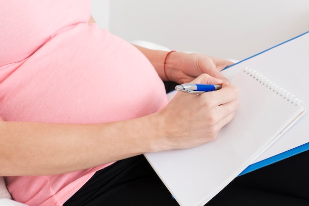 Close up of pregnant woman with clipboard