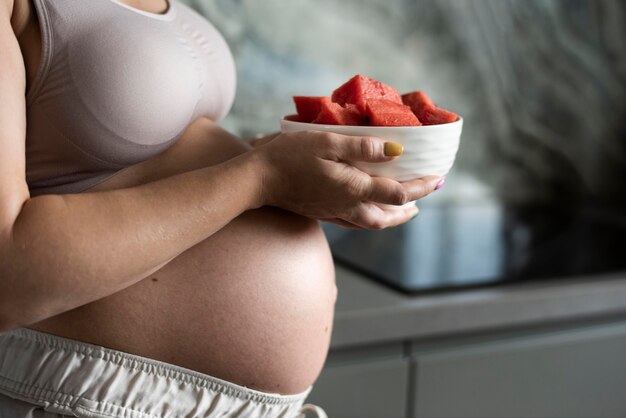 Close up pregnant woman with fruit bowl