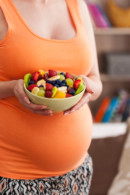 Free photo close up of pregnant woman with fruit salad