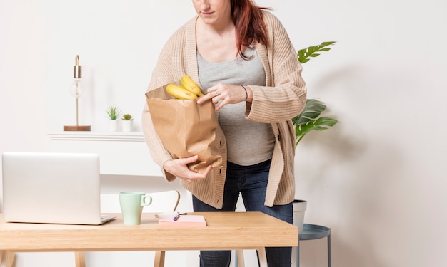 Крупным планом беременная женщина с продуктовой сумкой