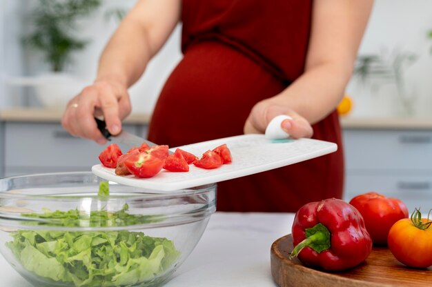 Крупным планом беременная женщина с помидорами
