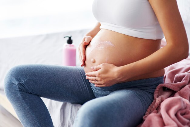 Close up of pregnant women applying moisturizer