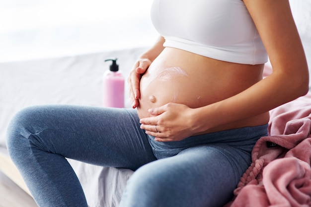 Close up of pregnant women applying moisturizer