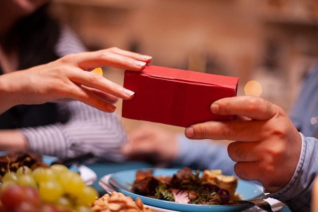 Close up of present box and couple having romantic dinner