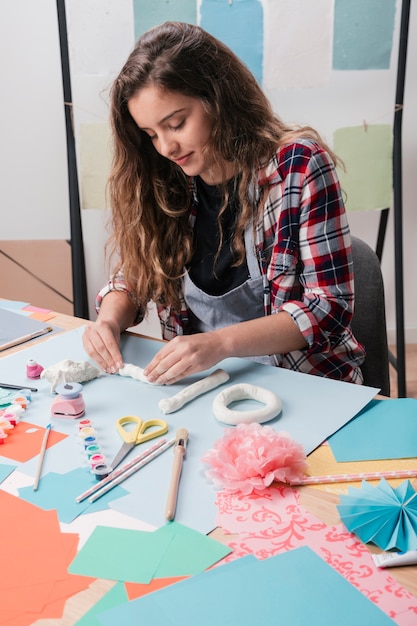 Close-up of pretty woman making craft using white clay