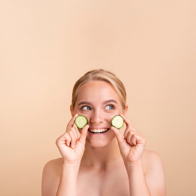 Free photo close-up pretty woman with cucumber slices and copy-space