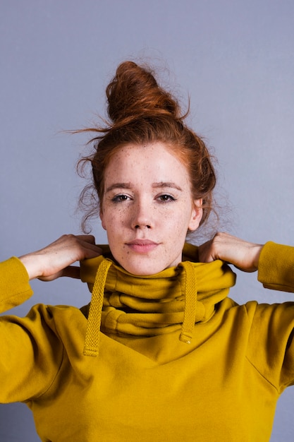 Free photo close-up pretty woman with hair bun and yellow hoodie