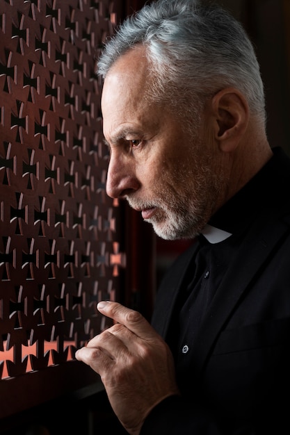 Close up priest listening to confession at church
