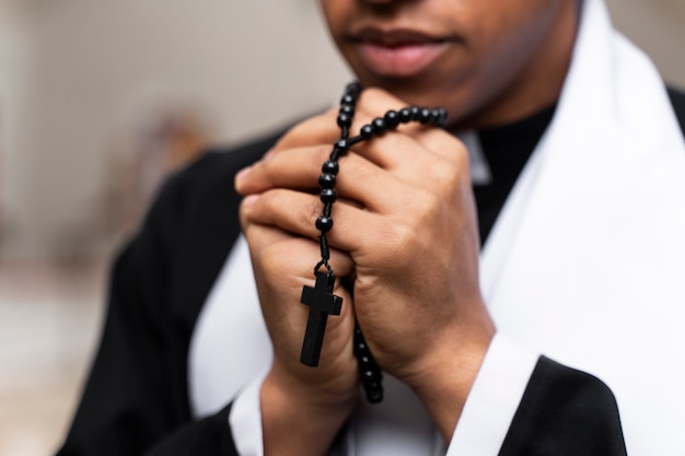 Foto gratuita chiuda sul sacerdote che prega con la croce