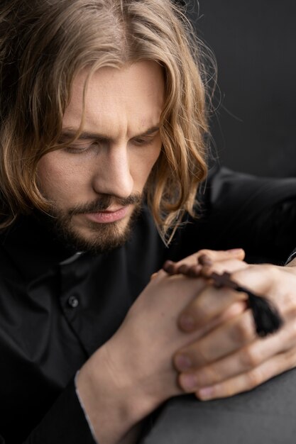 Close up priest praying with rosary