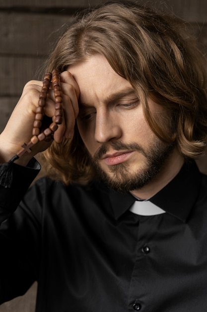 Foto gratuita chiuda sul sacerdote che prega con il rosario