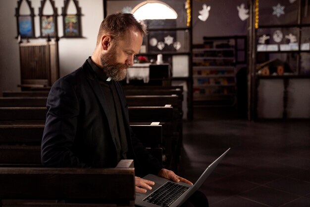 Крупный план священника с помощью ноутбука