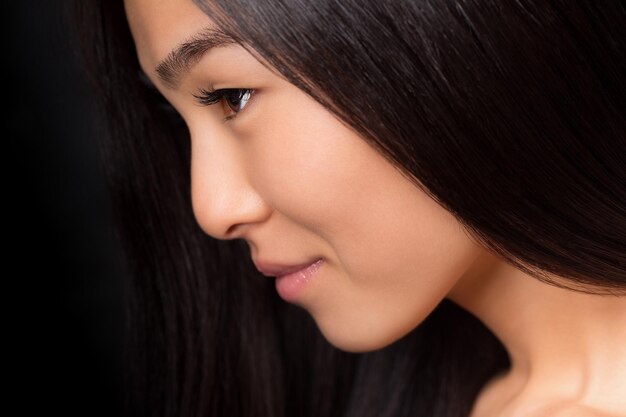 Close-up profile of asian lady with long black hair posing in studio.