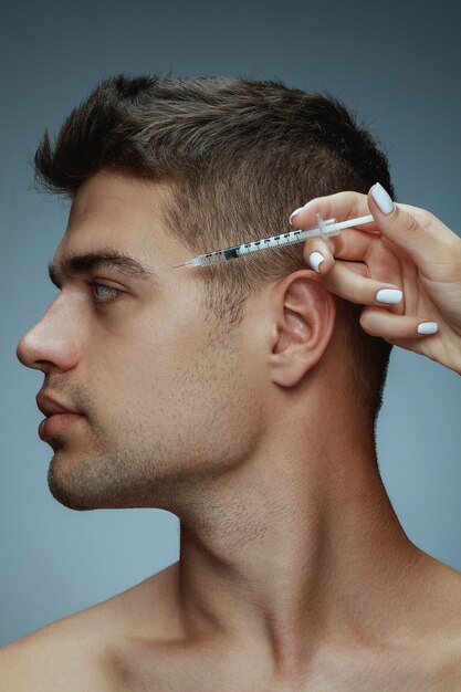 Close-up profile portrait of young man isolated on grey studio, filling surgery procedure