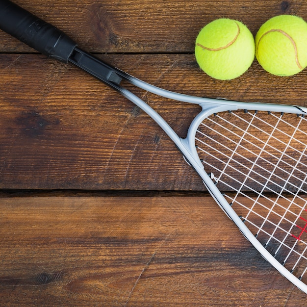 Foto gratuita primo piano della racchetta con due palline da tennis sul tavolo di legno