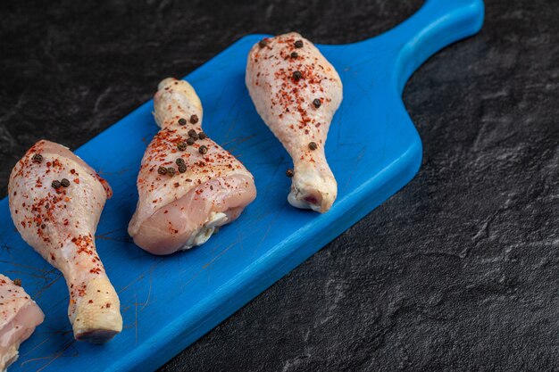 Close up raw chicken drumstick on wooden board.